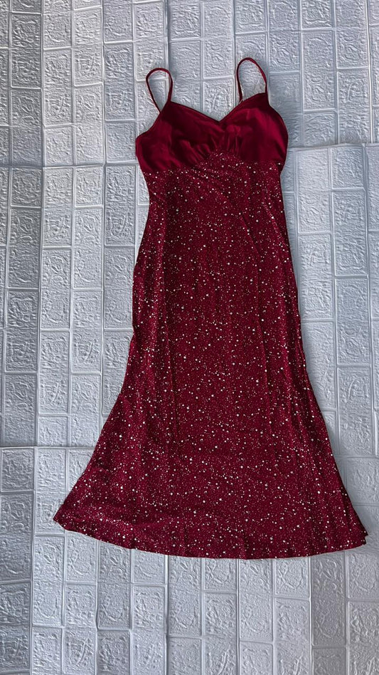 Red sparkly dress on a hanger against a textured gray wall